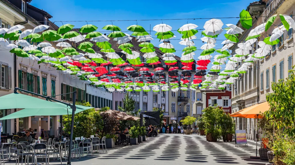 A Swiss street decorated with colorful hanging umbrellas, reflecting the vibrant diversity of professional environments.